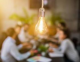 lightbulb in front of out of focus group of people at table